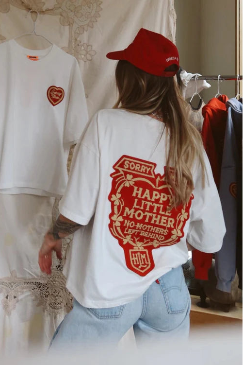 Person wearing a white t-shirt with red text and graphics, standing in a clothing store.