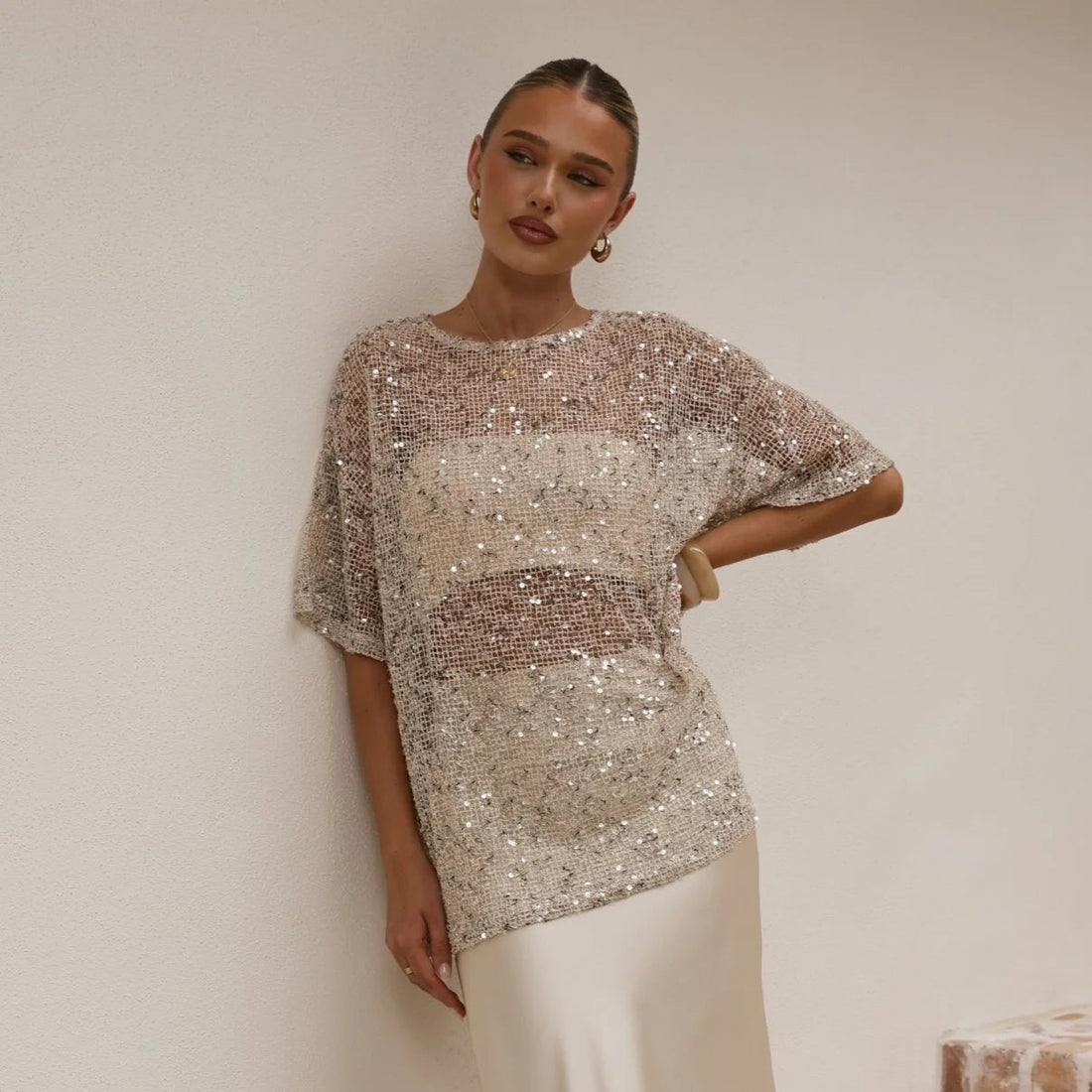 Woman wearing a sparkling top and white skirt on a staircase.