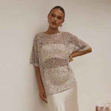 Woman wearing a sparkling top and white skirt on a staircase.