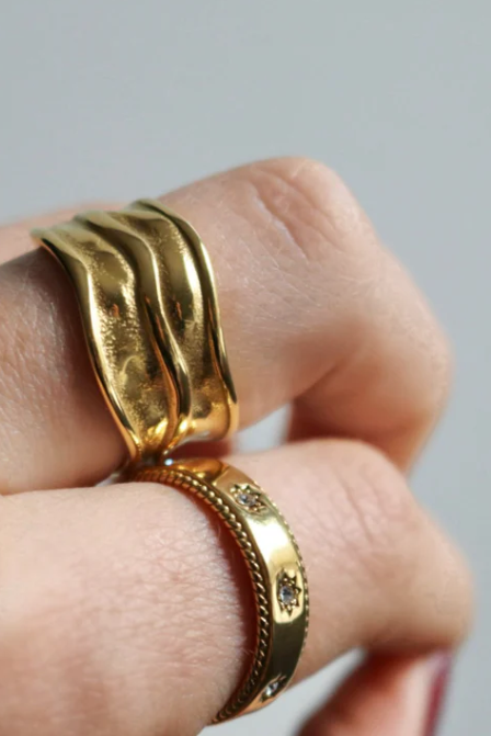Gold ring on a finger against a neutral background