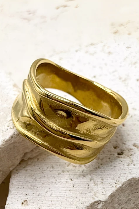 Gold ring on a textured beige surface