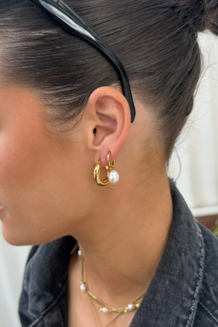 Close-up of a woman wearing gold hoop earrings with pearls.
