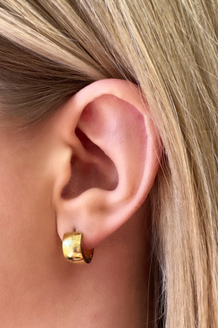 Gold hoop earring worn by a person with blonde hair.