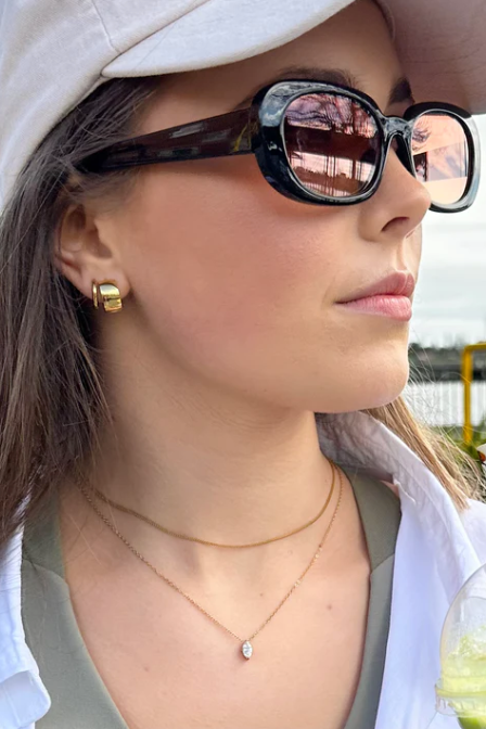 Gold hoop earring worn by a person with blonde hair.
