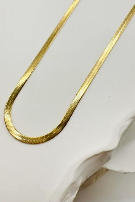 Gold necklace worn by a person with a blurred background
