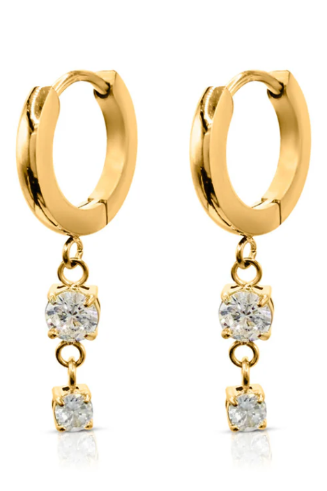 Gold hoop earring with a small diamond pendant worn by a person with blonde hair.