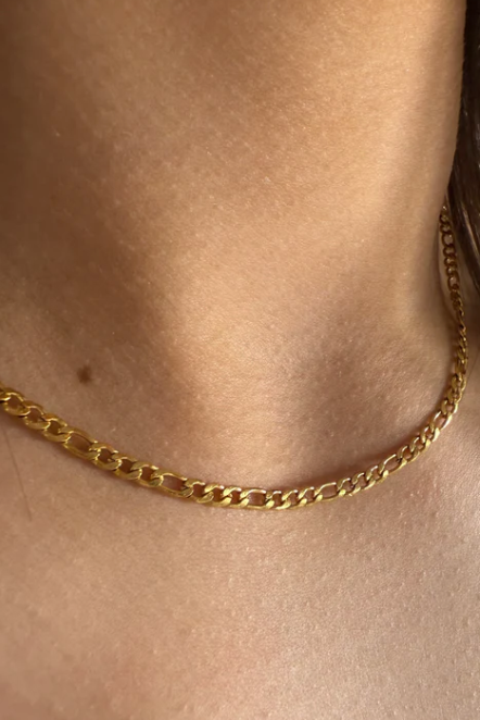 Gold chain necklace worn by a person with short hair.