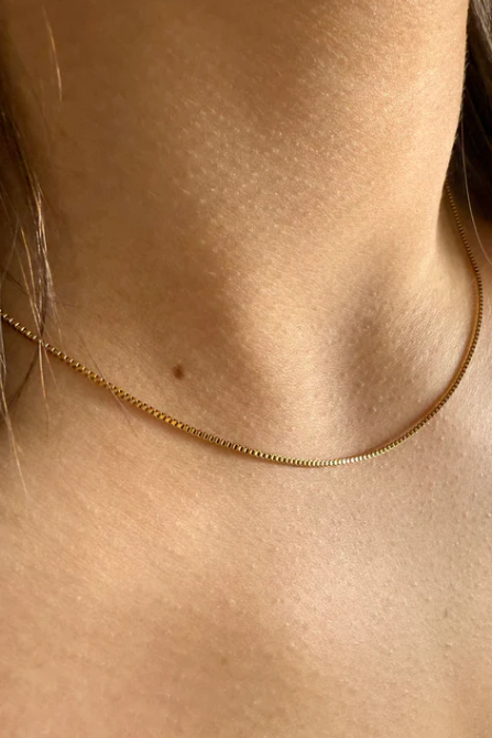 Gold necklace on a person's neck with a blurred background