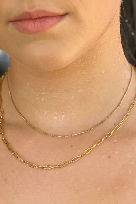 Close-up of a person wearing a gold chain necklace with a blurred background