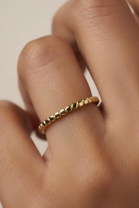 Gold ring on a finger against a neutral background