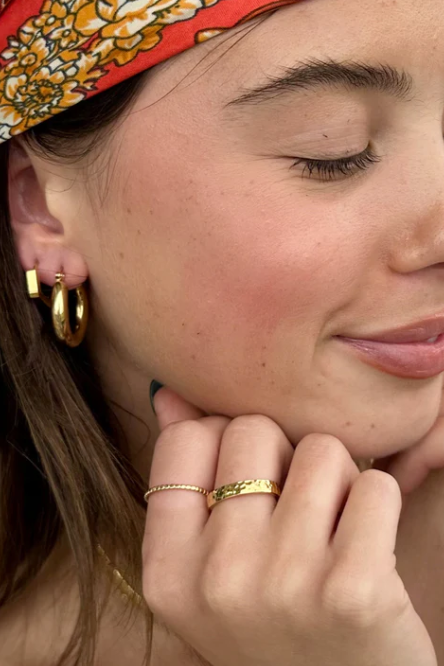 Gold ring on a finger against a neutral background