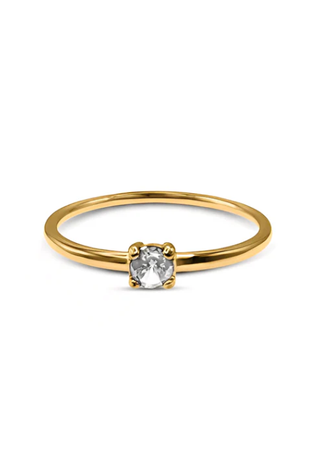 Gold ring with a diamond on a person's finger against a neutral background