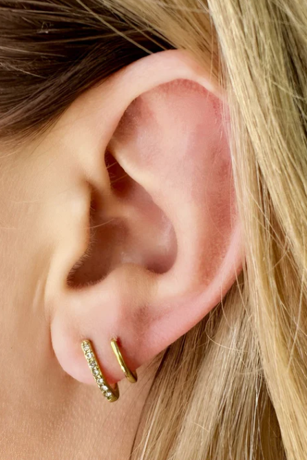 Close-up of an ear wearing gold hoop earrings with blonde hair.