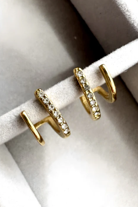Close-up of an ear wearing gold hoop earrings with blonde hair.