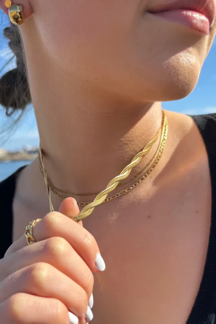 Close-up of a person wearing gold necklaces and earrings with a blurred background