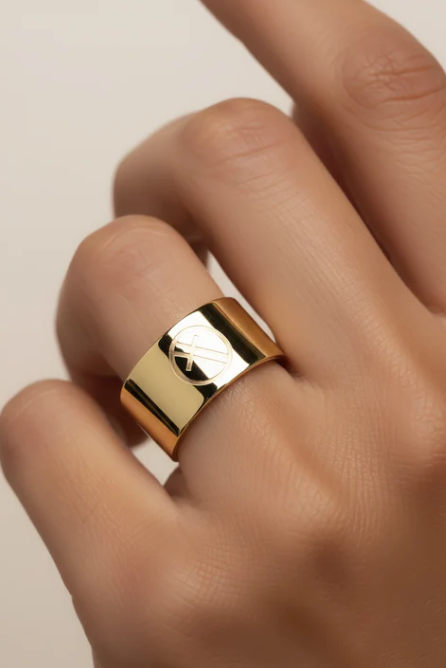 Gold ring on a person's finger against a neutral background