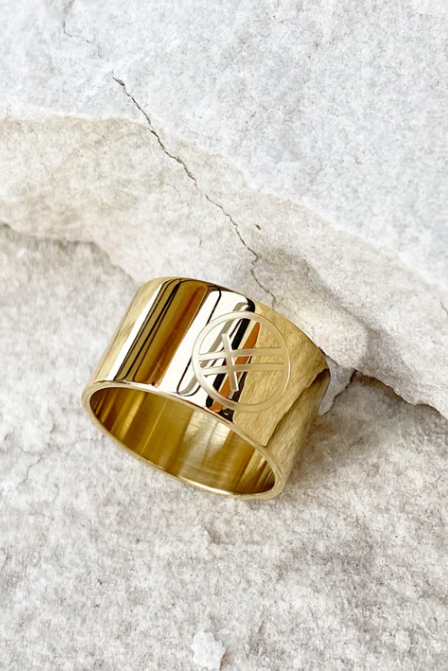 Gold ring on a person's finger against a neutral background