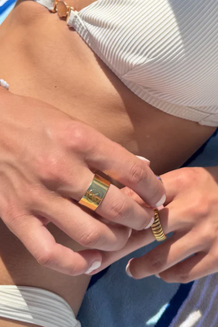 Gold ring with a logo on a textured stone surface