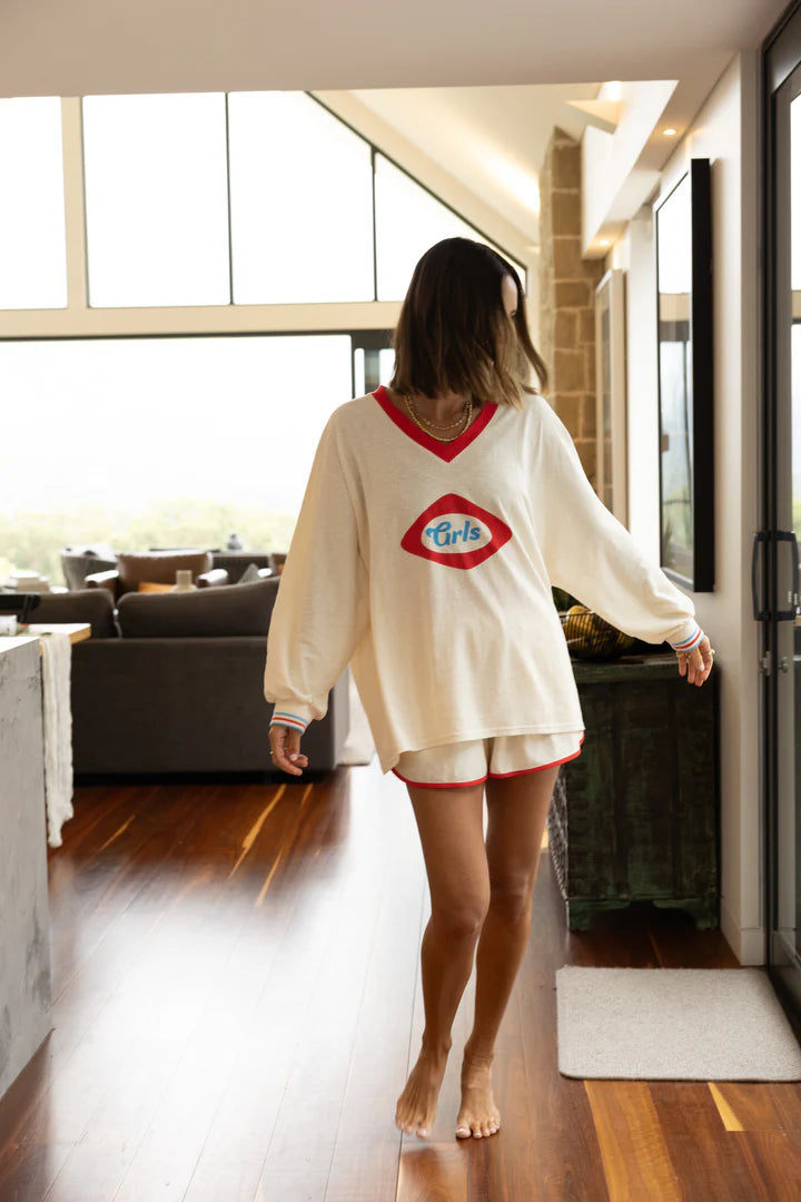 Woman in pajama set with a visible brand logo standing in a modern kitchen.