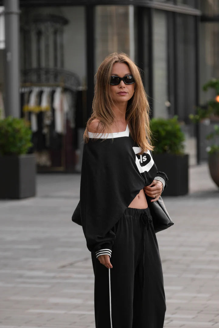 Woman wearing a black and white outfit with sunglasses on a city street.