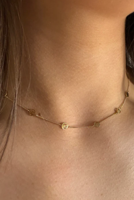 Gold necklace on a person's neck with a neutral background