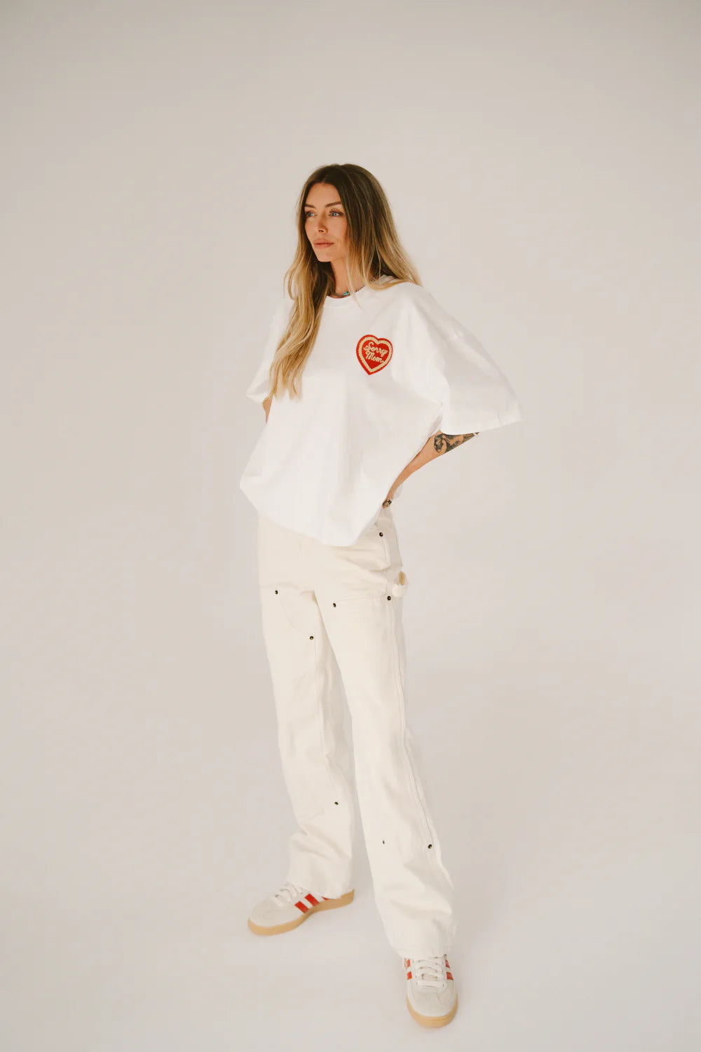 Woman wearing a white outfit with a red heart design on a plain background