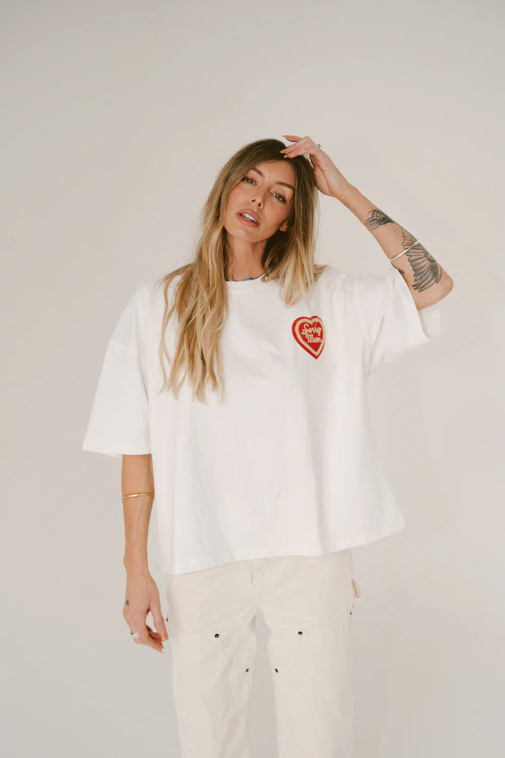 Person wearing a white t-shirt with red text and graphics, standing in a clothing store.