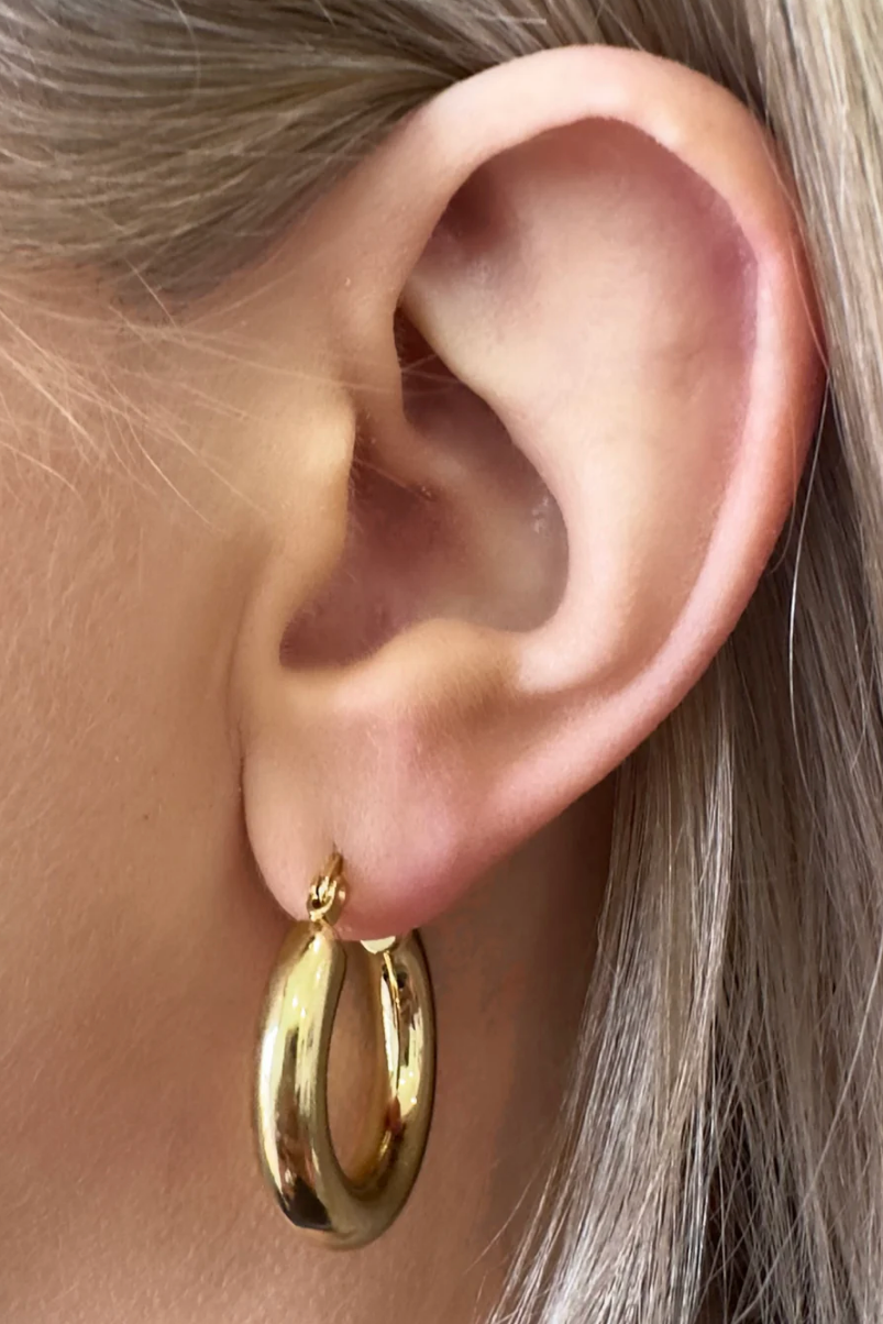 Gold hoop earring worn by a person with blonde hair.