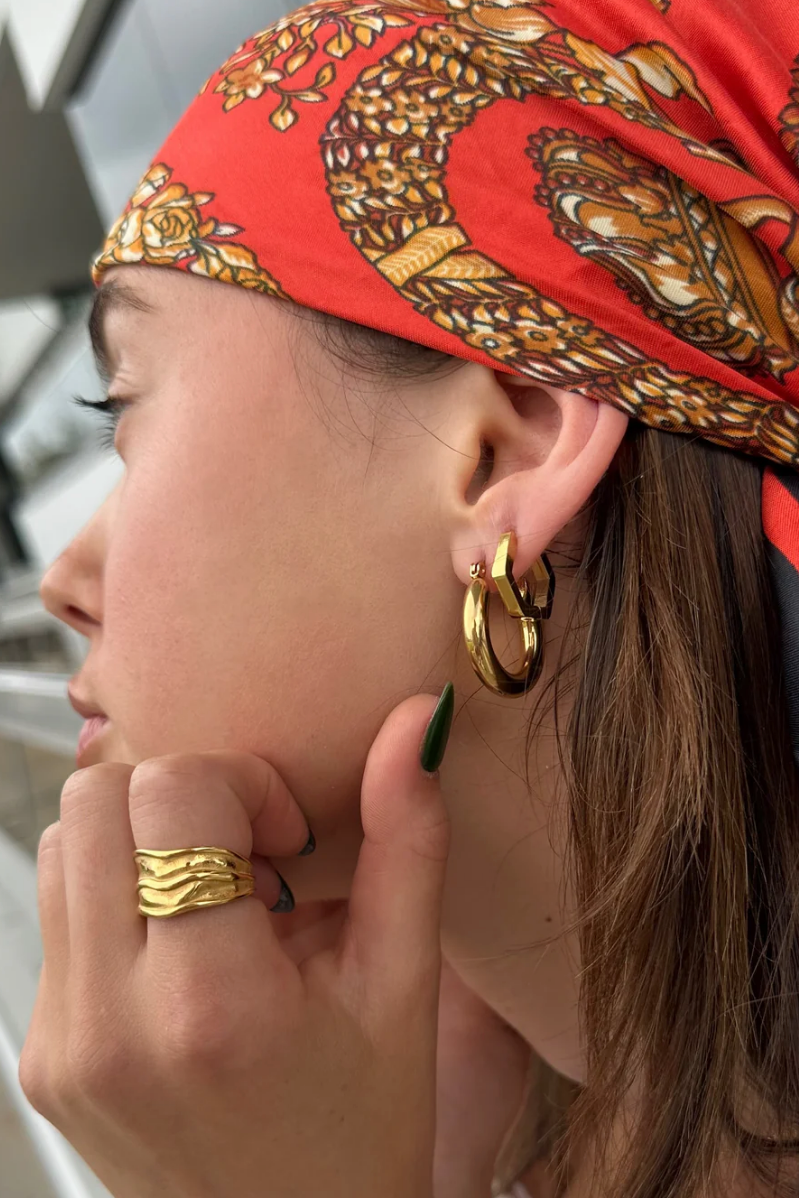 Gold hoop earring worn by a person with blonde hair.